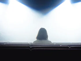 Eine Frau sitzt in einem Theatersaal
